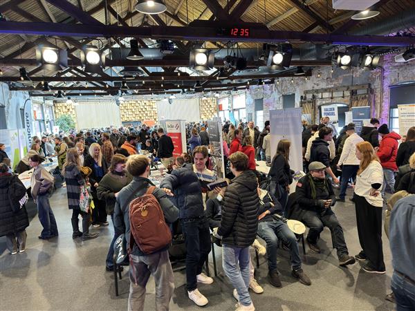 Mange mennesker står innendørs rundt flere standplasser