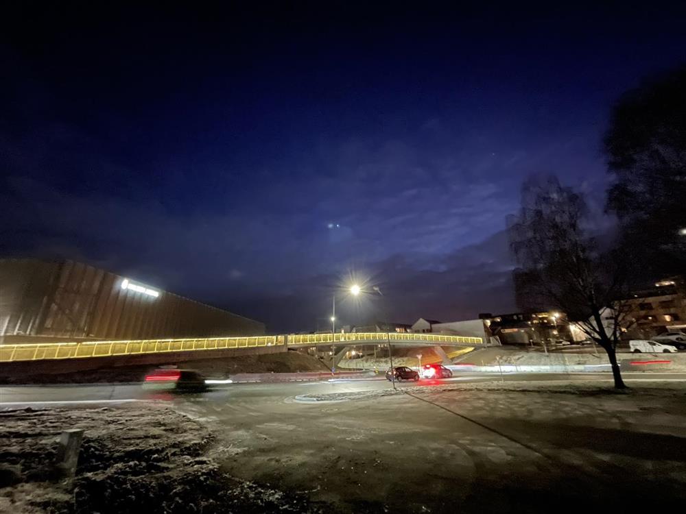Bro med lys langs rekkverket. Mørk himmel.  - Klikk for stort bilde