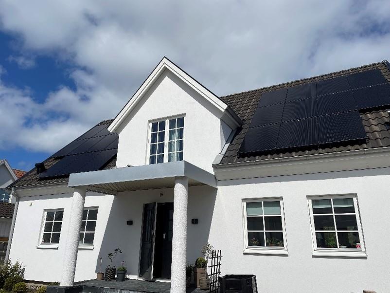 Et stort hvitt hus med solcellepaneler montert på taket - Klikk for stort bilde