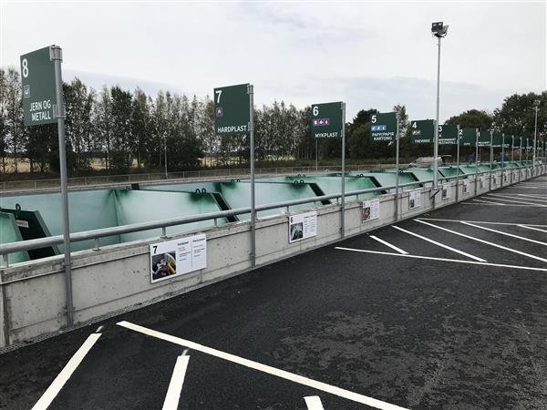 En lang rekke med grønne containere på en avfallsplass