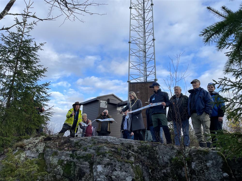 På bildet klipper varaordfører Linn Laupsa båndet i forbindelse med åpning av ny mobilmast i Enningdalen. Rundt henne står representanter fra Telenor, grunneier og andre beboere i Enningdalen. - Klikk for stort bilde