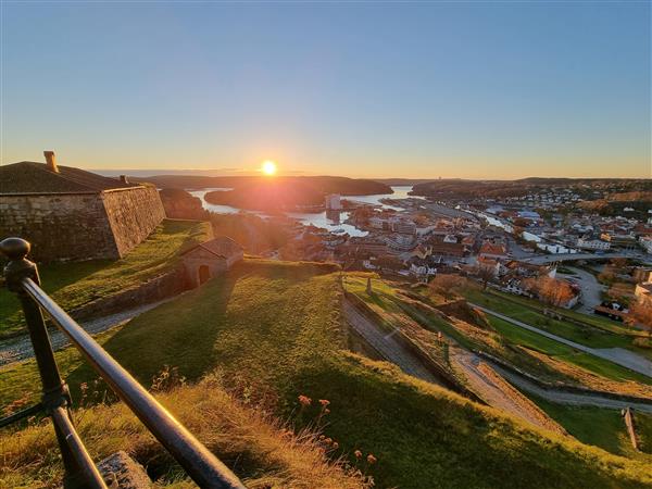 Utsikt fra Fredriksten festning mot Halden sentrum i en kraftig solnedgang.