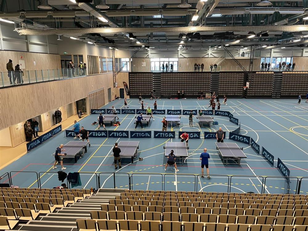 Åtte bordtennisbord på et gulv i en idrettshall. - Klikk for stort bilde