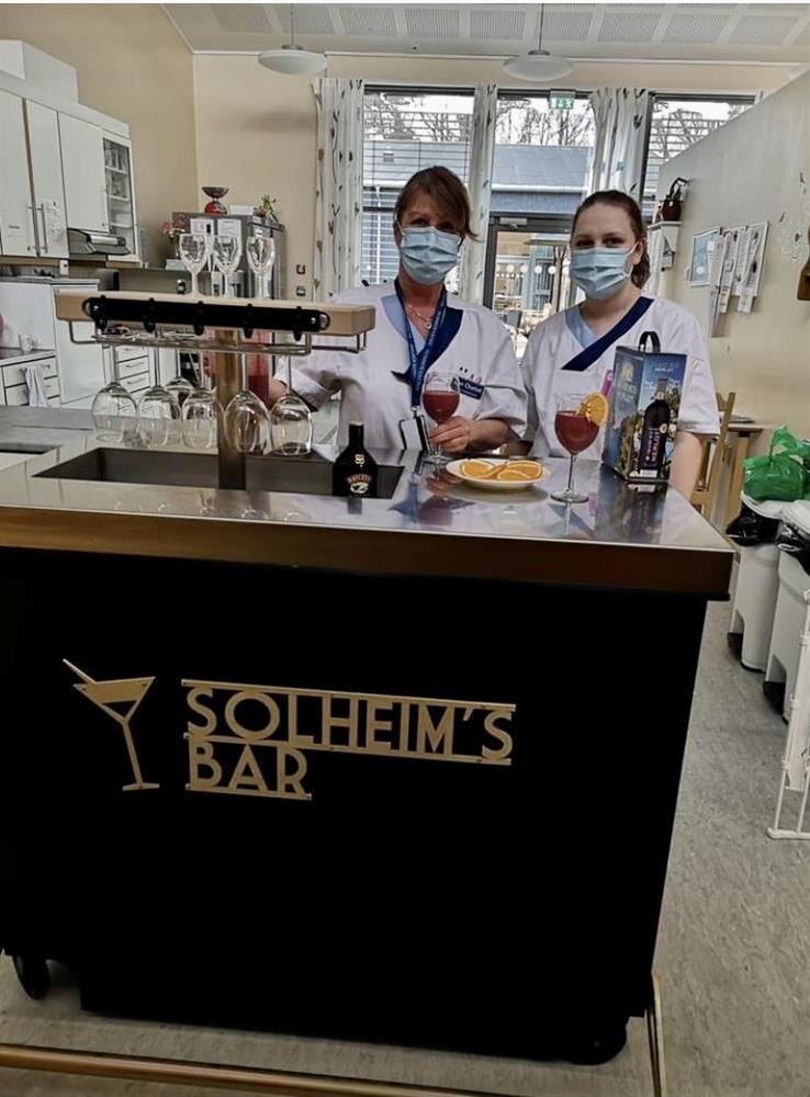 Ansatte betjener Solheim's Bar og serveringsbenk - Klikk for stort bilde